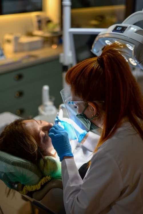 Dental professional using a curing light on a patient